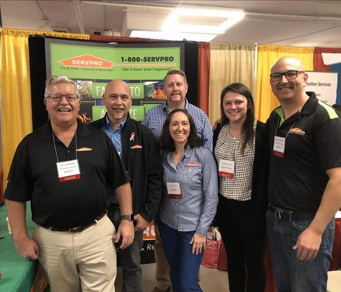 group of servpro employees standing in front of servpro sign at an event