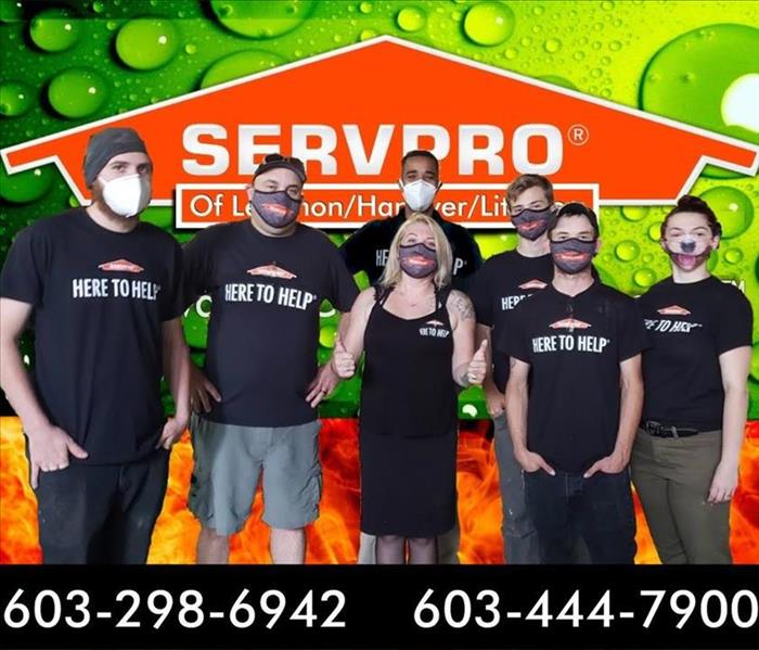 Group picture of SERVPRO employees wearing "Here to Help" shirts in front of SERVPRO background