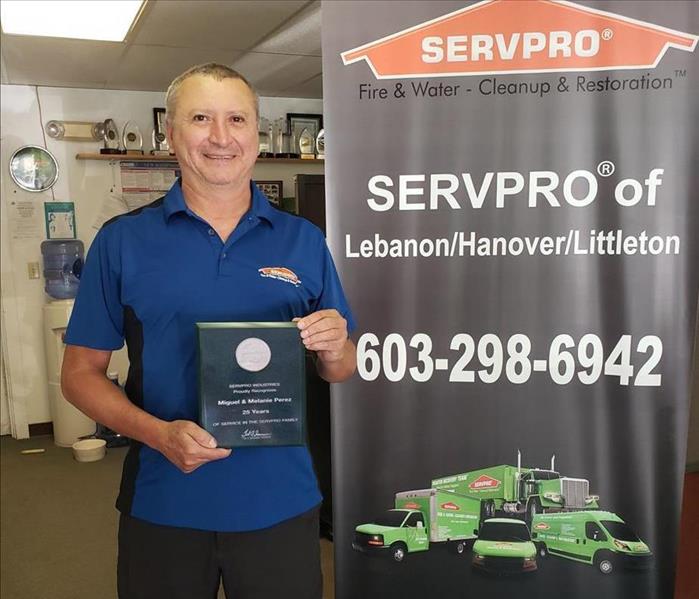 Man holding 25th anniversary plaque next to SERVPRO sign