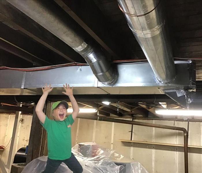 girl standing underneath ductwork in basement