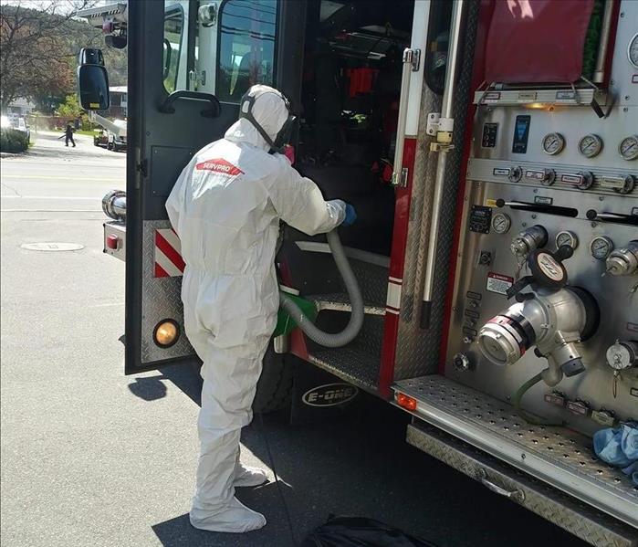 man in hazmat suit cleaning inside of fire truck