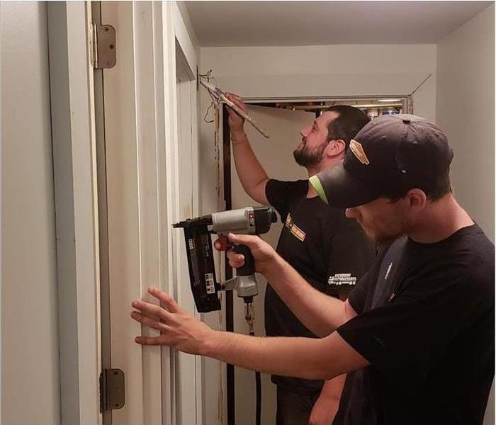 two servpro technicians doing construction and painting in home