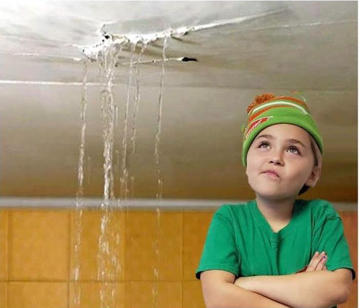Young girl looking up at water leaking from ceiling