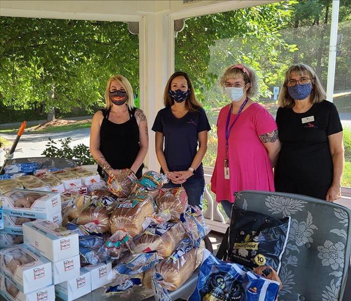 women standing behind table of donated goods